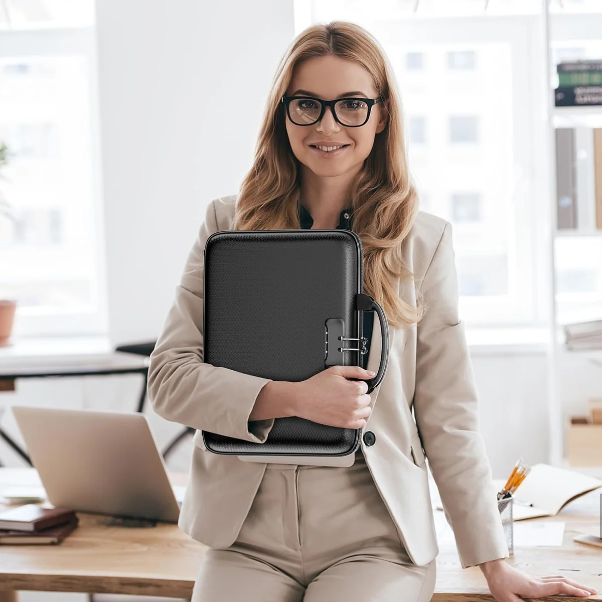 A woman at a desk holding the DocSafe Hard-Shell Fireproof File Organizer with Lock